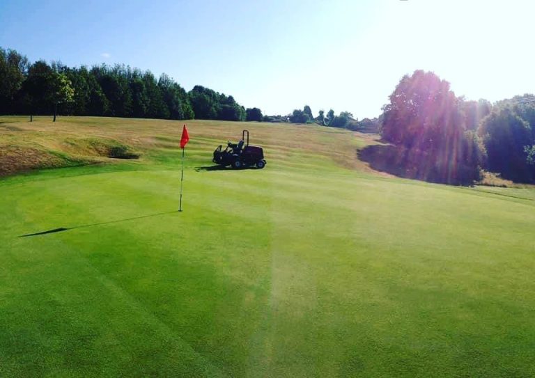 Greenkeeper mowing the course on a sunny day
